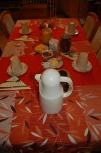 a table with a red table cloth with a tea pot on it at Caux-Breizh in Rohan
