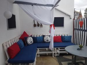 De Aar的住宿－Obrigado Guest House，庭院里配有蓝色沙发,提供红色和蓝色枕头