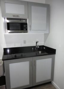 a kitchen with a sink and a microwave at Lotus Boutique Inn and Suites in Ormond Beach