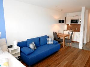 a blue couch in a living room with a kitchen at Apartment Möwe in Meersburg
