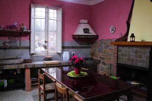 cocina con paredes rosas, mesa y chimenea en Il Tiglio, en Monsagrati