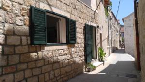 a brick building with green shutters on a street at privat room with privat bathroom David in Hvar