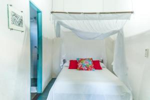 a bedroom with a white bed with a canopy at Casa Aconchegante em Caraíva - Casas Do San in Caraíva