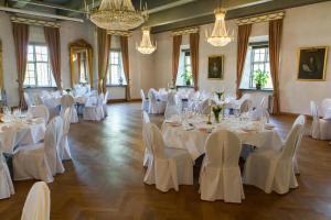 Cette chambre comprend des tables et des chaises blanches ainsi que des lustres. dans l'établissement Sundbyholms Slott, à Sundby