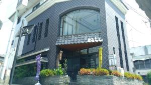 un edificio con una ventana y flores delante de él en Guest House Kuranomachi ゲストハウス蔵の街 en Tochigi