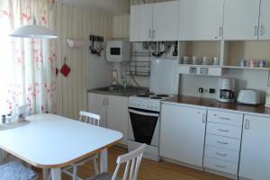 una cocina con armarios blancos, una mesa blanca, una mesa y una mesa blanca en Helge Guest House en Valga