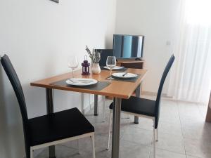 una mesa de madera con 2 sillas y copas de vino en Apartments and Rooms Saric, en Jadrija