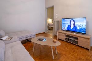 een woonkamer met een bank en een flatscreen-tv bij Artemis - Athens Deluxe City Center Apartment in Athene