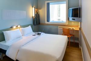 um quarto com uma cama branca, uma secretária e uma janela em ibis budget Sao Bernardo do Campo em São Bernardo do Campo
