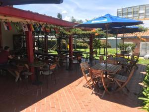een patio met tafels en stoelen en een parasol bij Hostal El Hangar in Rionegro