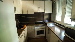 La cuisine est équipée de placards blancs, d'un évier et d'une cuisinière. dans l'établissement Apartments Madrid Eliptica, à Madrid