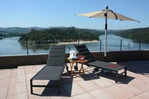 a patio with two chairs and a table and an umbrella at Figurino do Douro in Melres