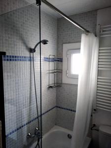 een badkamer met een bad en een douche met een raam bij Suitur Atico Sitges Centro in Sitges