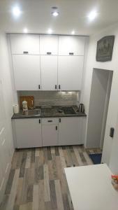 a kitchen with white cabinets and a wooden floor at Tawerna Rybaki Old Town in Gdańsk