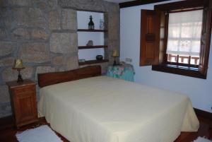 een slaapkamer met een bed en een stenen muur bij Agro-Turismo Quinta do Pendao in Santa Cruz da Trapa