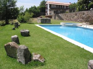 een zwembad in een tuin met rotsen eromheen bij Agro-Turismo Quinta do Pendao in Santa Cruz da Trapa