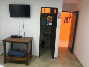 een kamer met een badkamer met een televisie en een tafel bij Hostal El Hangar in Rionegro