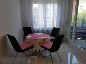 a table with four chairs and a table with pink cushions at Loft Orchidee in Überlingen