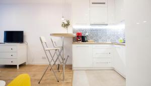 クラクフにあるRakowicka Apartamentの白いキャビネット、テーブルと椅子付きのキッチンが備わります。