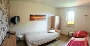 sypialnia z łóżkiem i telewizorem na ścianie w obiekcie Ferienhaus Chrissy w mieście Loissin