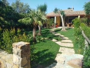 a garden with palm trees and a stone wall at Casa Alessia in Villasimius
