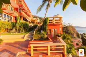 a building with a bench next to the ocean at Hotel Irma in Zihuatanejo