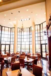 una sala da pranzo con tavoli, sedie e finestre di The Cook Hotel & Conference Center a Baton Rouge