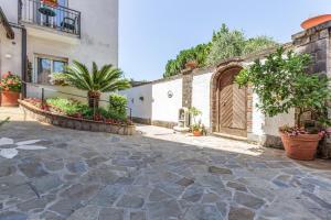 a house with a stone courtyard with a wooden door at Hotel La Pergoletta in SantʼAgata sui Due Golfi