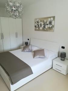 a white bedroom with a large bed and a chandelier at Apartment Chuck in Krk