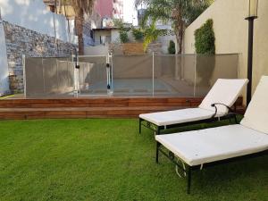 two white benches sitting on the grass in a yard at Apartamentos Centricos in Mendoza