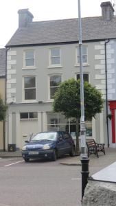 a blue car parked in a parking lot in front of a building at Rossa House in Rosscarbery