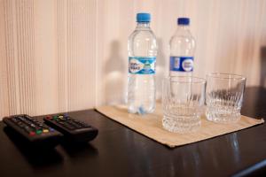 two bottles and glasses on a table with a remote control at Charivne Ozero in Korostyshiv