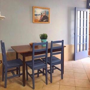 a dining room table with blue chairs and a painting on the wall at Alice's Apartment in Castellammare del Golfo