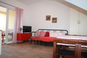 um quarto com uma cama e um sofá vermelho em Apartman Luka em Viganj