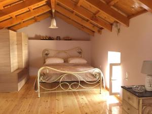 1 dormitorio con 1 cama en una habitación con suelo de madera en Villa Maria Kythera, en Katsoulliánika
