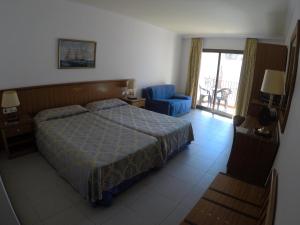 a bedroom with a bed and a blue chair at Hostal Vila del Mar in Lloret de Mar