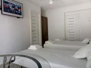 a white bedroom with two beds and a tv on the wall at Pension Centro in Guardamar del Segura