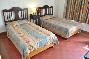 two beds in a room with a red tile floor at Hotel 5a Avenida in Monterrey