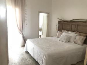 1 dormitorio con cama blanca y cabecero de madera en I quartini, en Maruggio