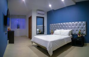 a bedroom with a large bed with a blue wall at Hotel Mocoa Samay in Mocoa