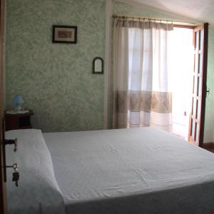 1 dormitorio con 1 cama blanca grande y ventana en Casa Aurora en Dorgali