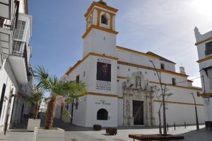 eine Kirche mit einem Uhrturm auf einem Gebäude in der Unterkunft Hospederia 1881 in Chiclana de la Frontera
