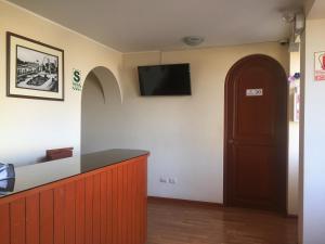 una sala de espera con puerta y TV en la pared en Hotel Arunta, en Tacna