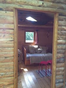 1 dormitorio en una cabaña de madera con 1 cama y 2 taburetes en Cabane Escargot du centre UnisVers en Peyrat-le-Château