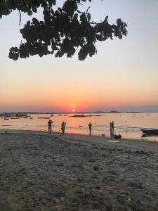 un grupo de personas de pie en una playa al atardecer en Casa piscina próxima praia, en Florianópolis