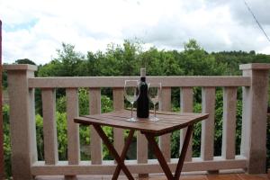 a bottle of wine and two glasses on a wooden table at Casa do Bouza Vello in Sober