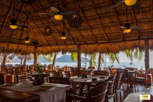 um restaurante com mesas e cadeiras e vista para o oceano em Hotel Villa Mexicana em Zihuatanejo