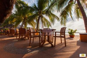 a table and chairs on the beach with palm trees at Hotel Villa Mexicana in Zihuatanejo