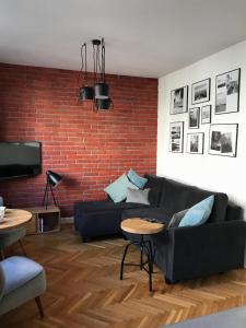 a living room with a black couch and a brick wall at Warszawa Hoża in Warsaw