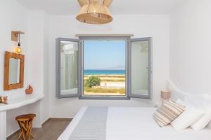 a bedroom with a large window with a view of the ocean at Salinus Villas in Plaka